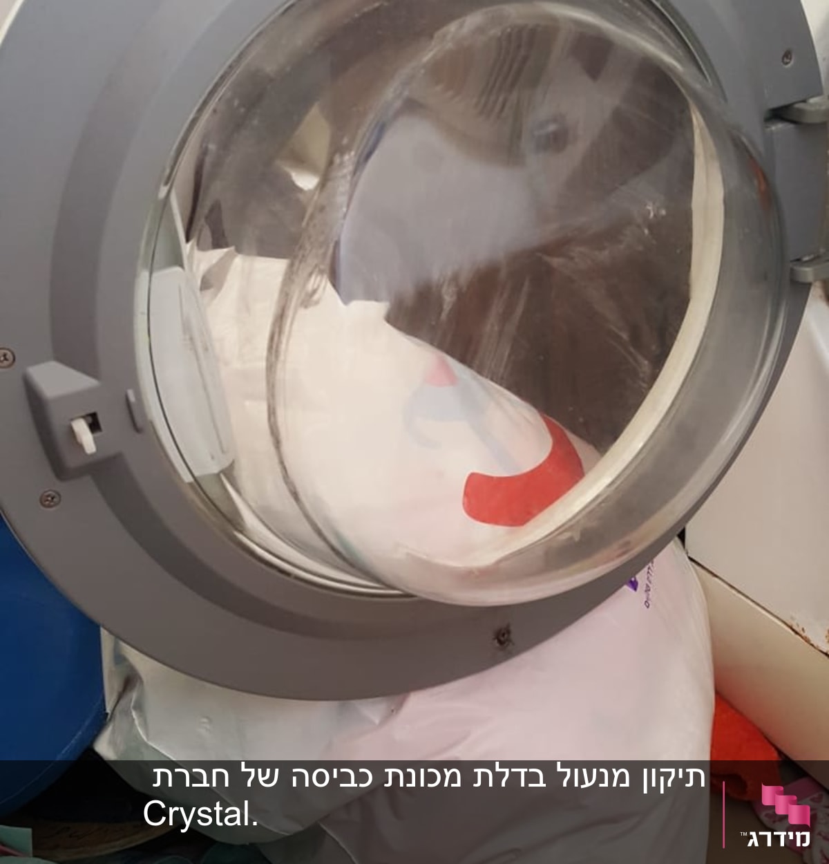דלת מכונת כביסה פתוחה עם בגדים בפנים